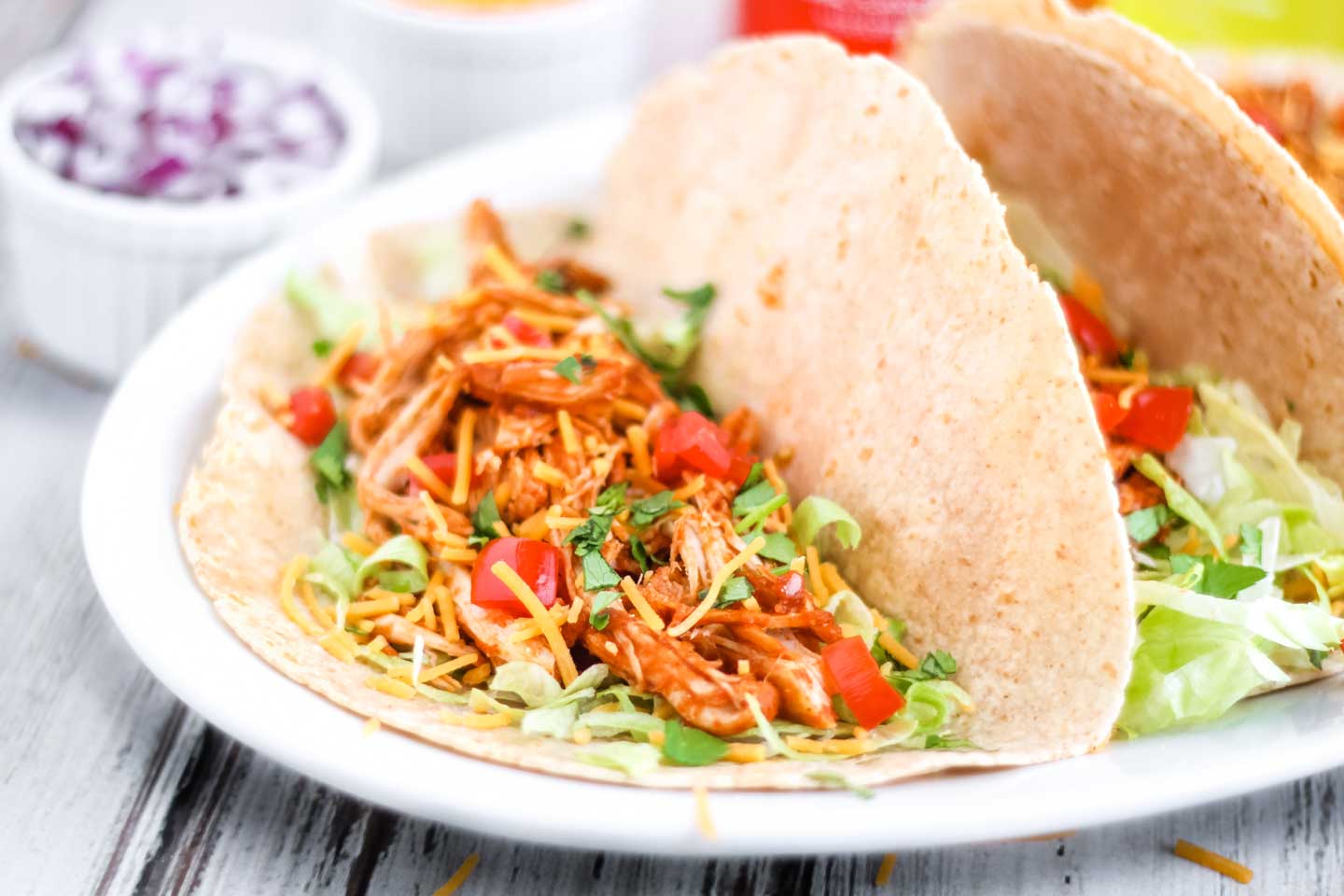 These clay pot chicken tacos served on whole wheat tortillas, instead of corn. Lined in a serving dish and sprinkled with lettuce, cheese and tomato.