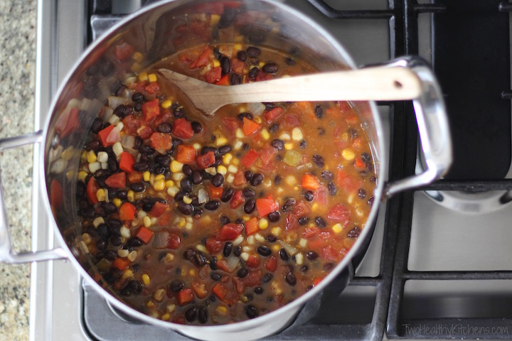 overhead of vegetarian chili in big pot on the stove, filled with corn, black beans and tomato chunks