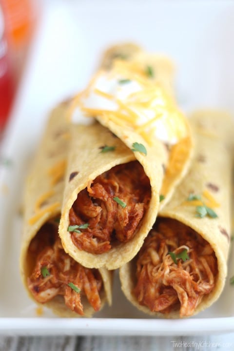 Older version of the photo showing 3 rolled tacos, stacked on a rectangular white plate, made simply of meat wrapped in corn tortillas.