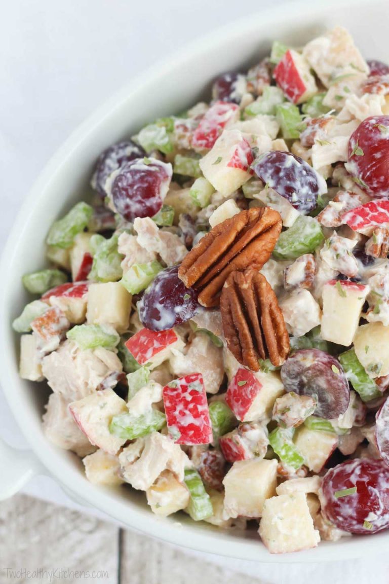 Overhead closeup of chicken salad in white, oval serving bowl, garnished with a couple pecans.