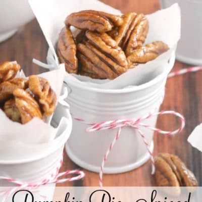 Closeup of finished nuts in small white gift pails tied with holiday string, text overlay "Pumpkin Pie Spiced Candied Pecans".