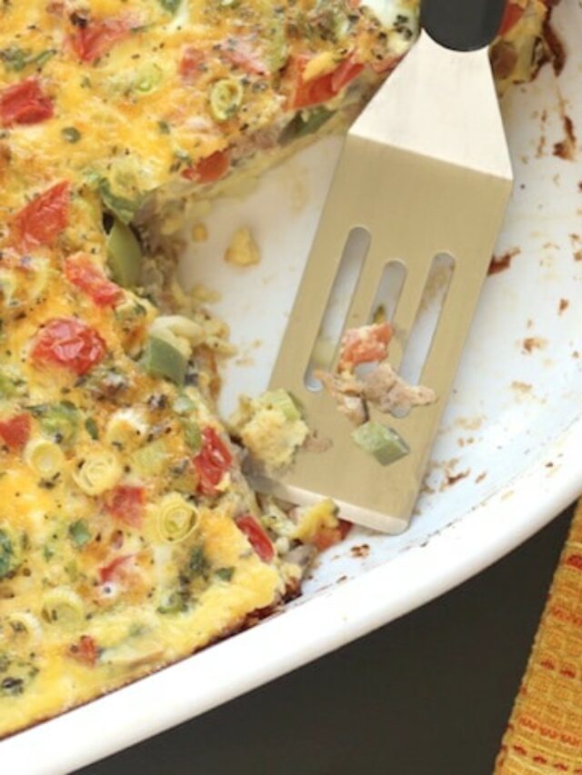 Overhead scene with one piece of egg bake on small white plate on yellow cloth, with casserole dish and scoop next to it.