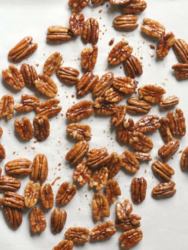 Flatlay of pecans after they've been candied, spread on white paper to cool and harden.