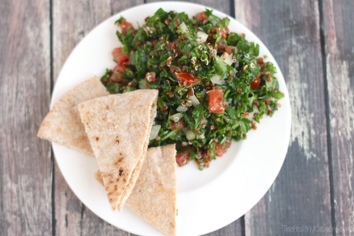 Serving of tabouli on small white plate with three wedges of pita bread.