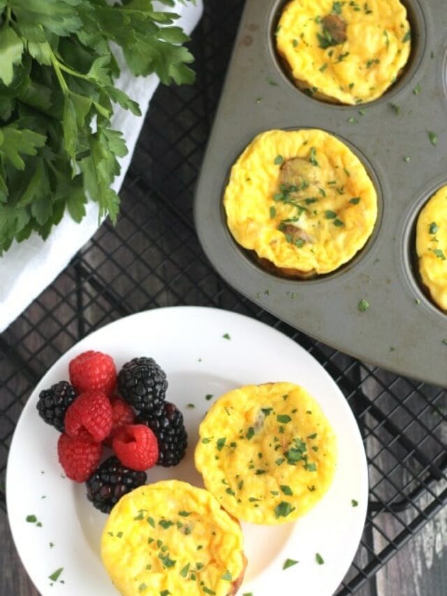 Baked egg muffins still in muffin pan and also 2 removed to white plate and served with berries.