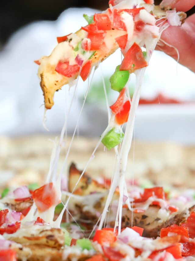 Side view closeup of one french fry getting pulled out of serving platter with gooey cheese strings.