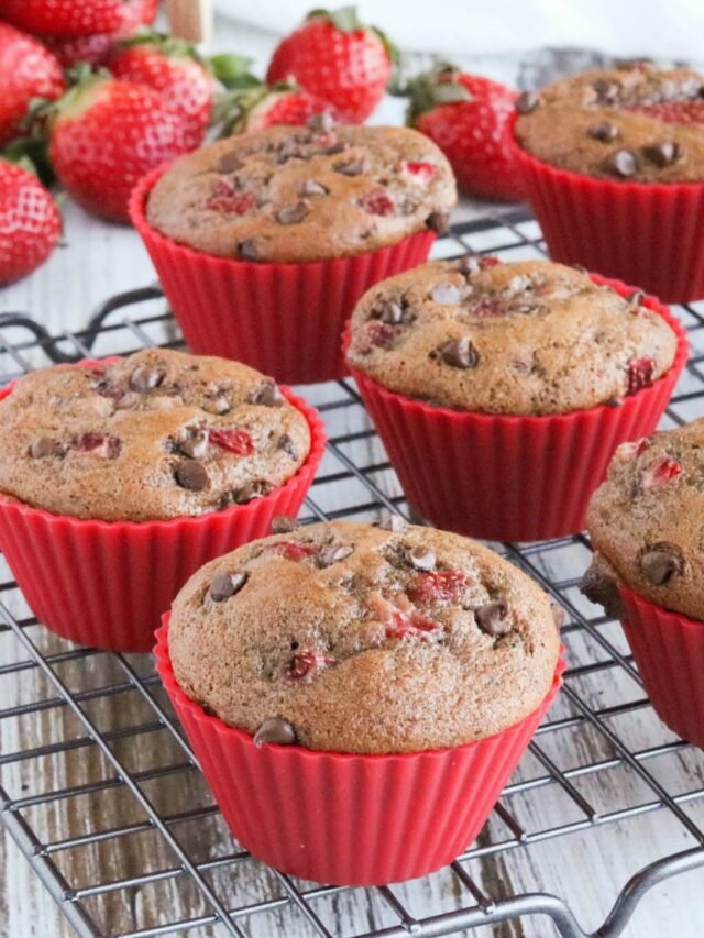 Closeup of muffins after baking, on cooling rack with berries in background.