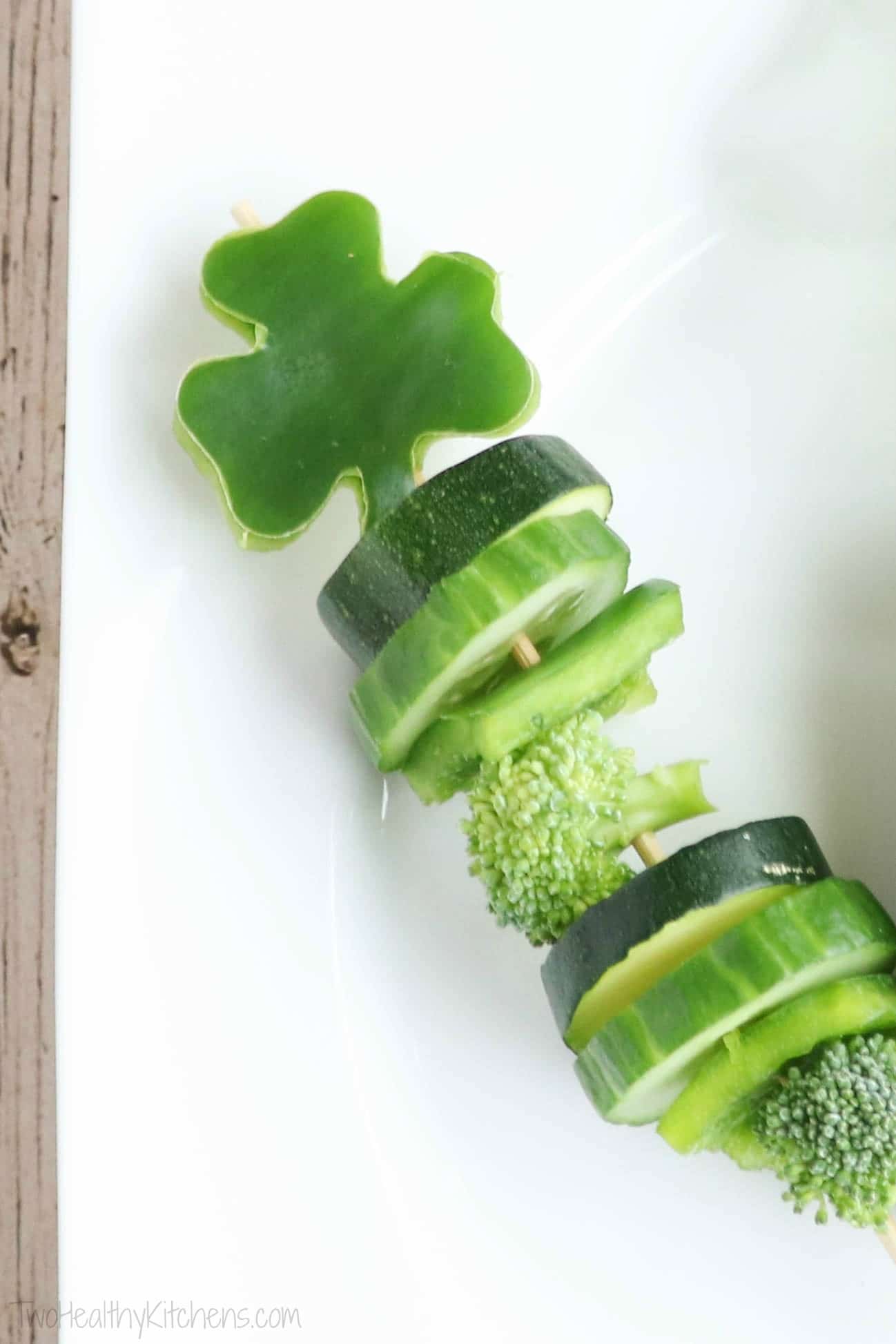 Closeup of one shamrock-topped skewer with rounds of cucumbers and zucchini, slices of green pepper and pieces of broccoli.