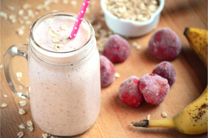 Smoothie in handled Mason jar with pink dotted straw; extra ingredients alongside.