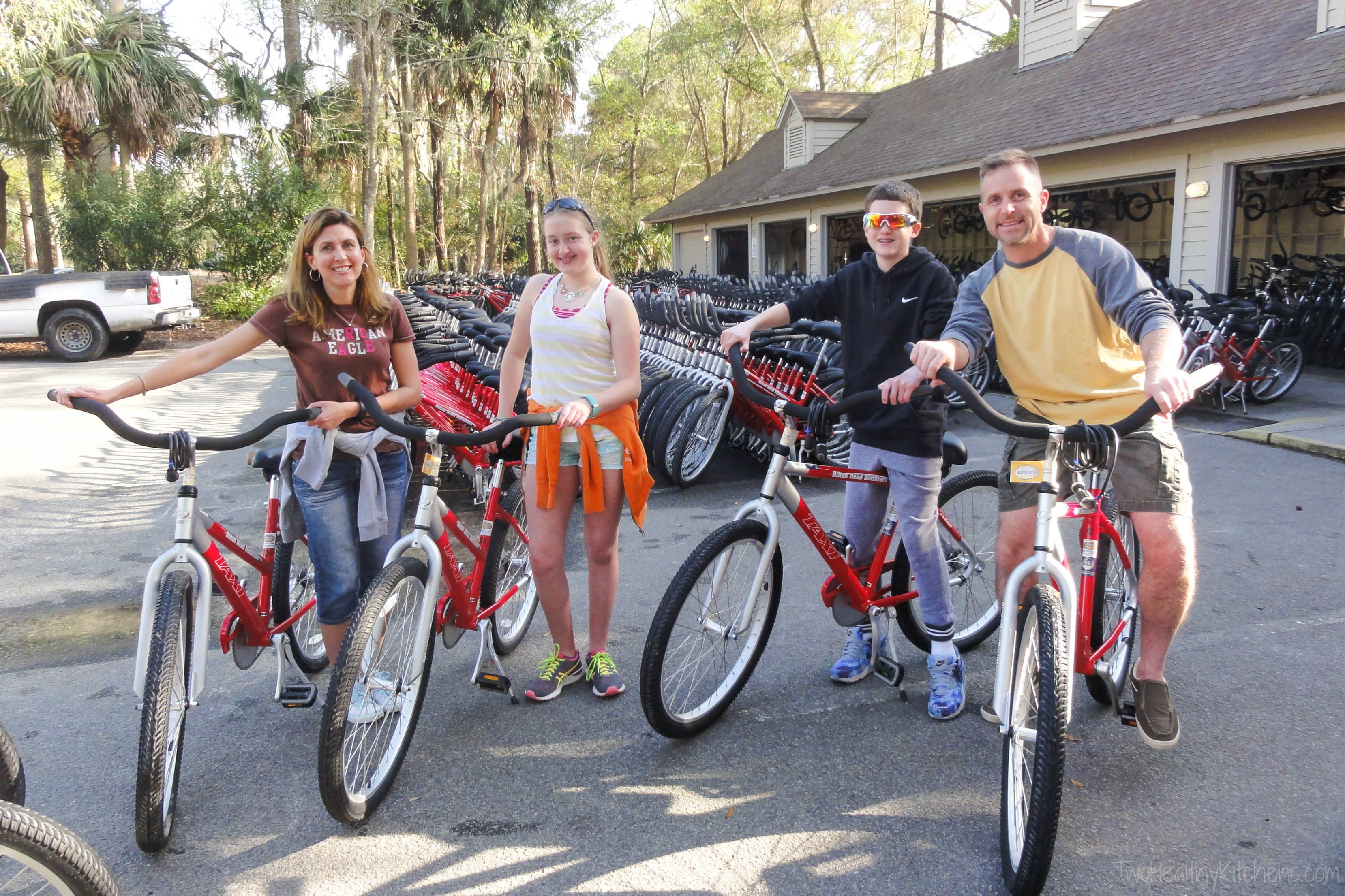 Family posed with red bikes in front of bike rental shop.