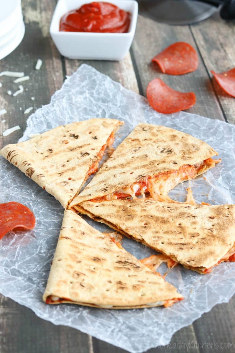 4 quesadilla wedges on white paper with cheese gooing out between and extra sauce and pepperoni in background.