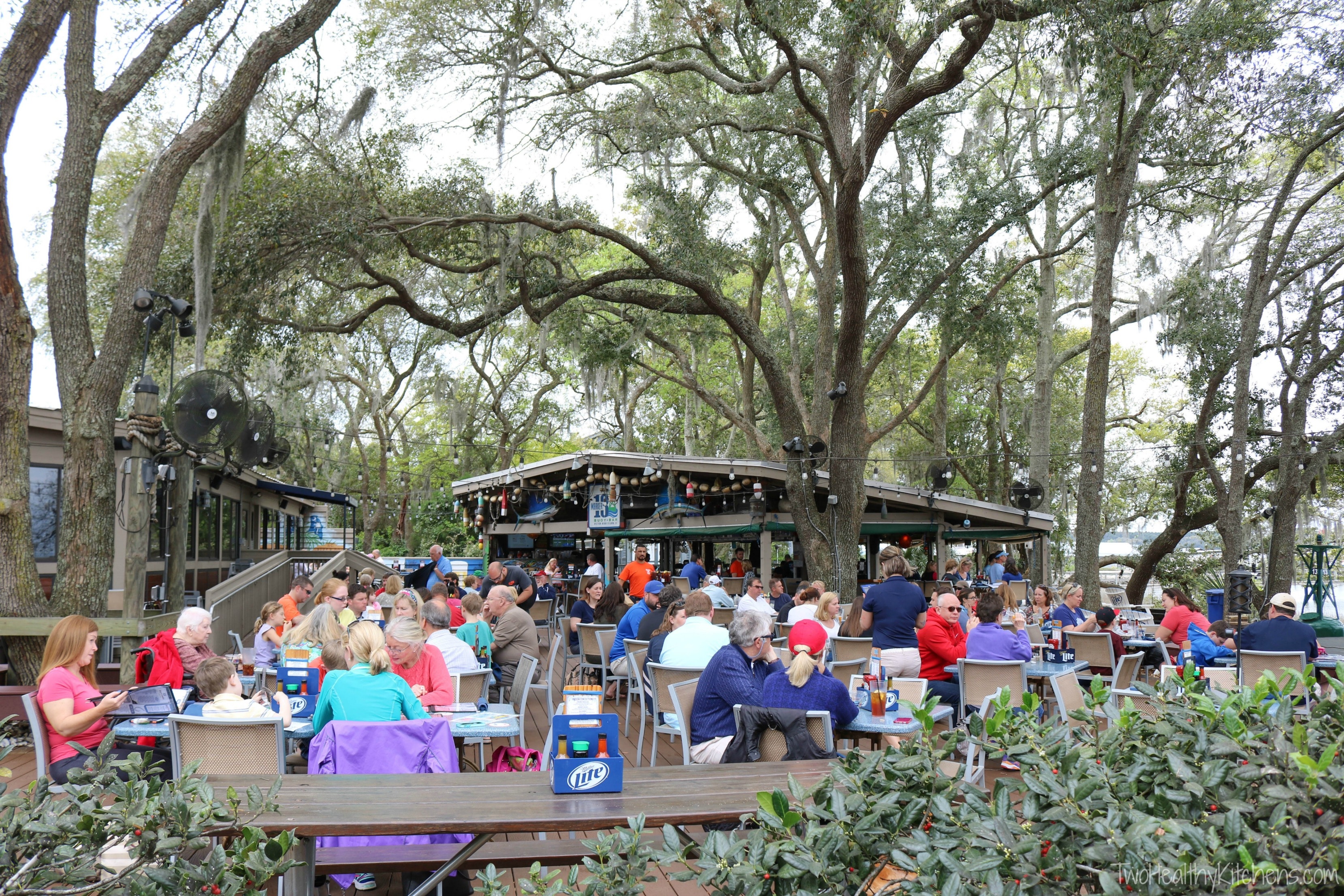 Diners at outdoor back patio under big trees. 