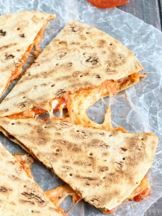 One quesadilla cut into 4 wedges on wax paper, with extra pepperoni and dish of pizza sauce nearby.