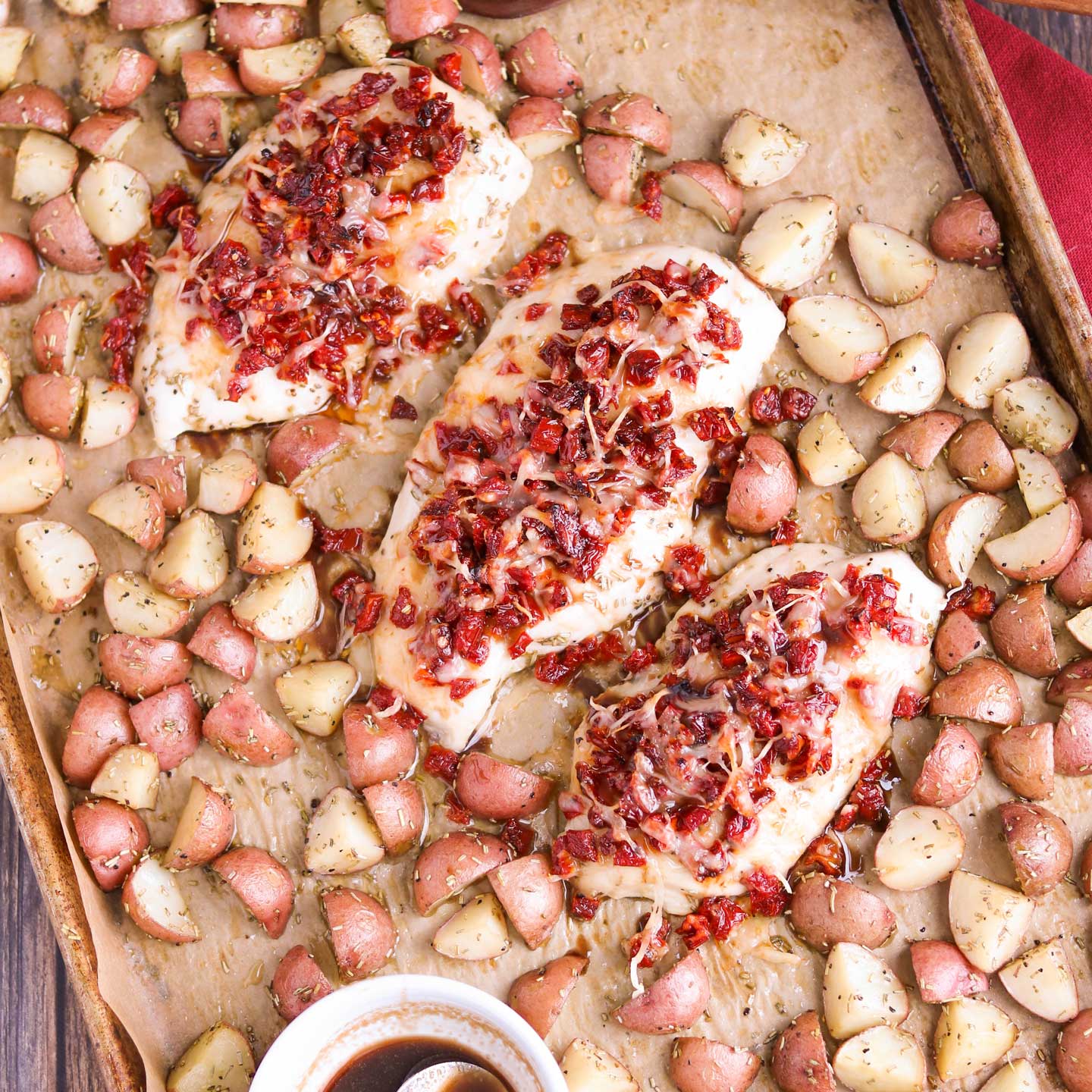 Incredibly delicious, with such easy cleanup! This sheet pan chicken dinner recipe features tender, juicy chicken breasts and perfectly baked redskin potatoes. All accented with rosemary, crowned with a scrumptious topping of sun-dried tomatoes and Italian cheeses, then finished with a honey-balsamic drizzle! This sheet pan supper recipe takes chicken and potatoes to a whole new level! Easy enough for weeknight dinners (make-ahead tips!), special enough for company! | www.TwoHealthyKitchens.com