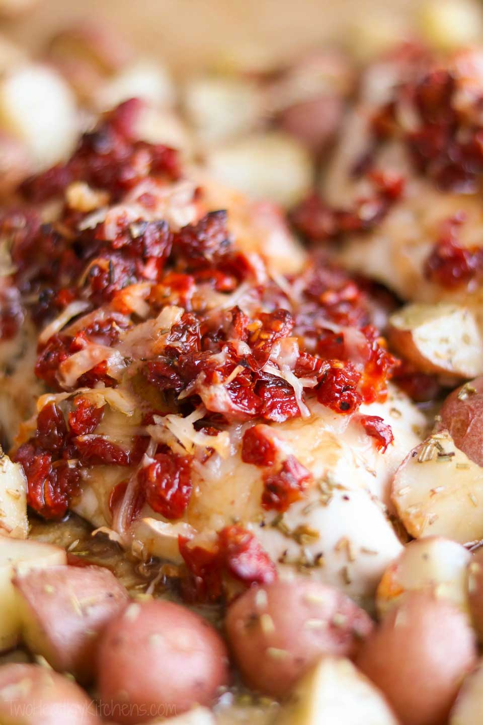 Incredibly delicious, with such easy cleanup! This sheet pan chicken dinner recipe features tender, juicy chicken breasts and perfectly baked redskin potatoes. All accented with rosemary, crowned with a scrumptious topping of sun-dried tomatoes and Italian cheeses, then finished with a honey-balsamic drizzle! This sheet pan supper recipe takes chicken and potatoes to a whole new level! Easy enough for weeknight dinners (make-ahead tips!), special enough for company! | www.TwoHealthyKitchens.com