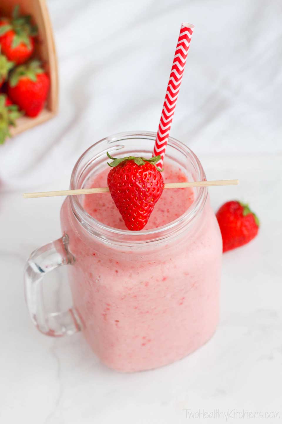 Strawberry-Banana Smoothie in a glass mug, decorated with a striped straw and a skewered strawberry