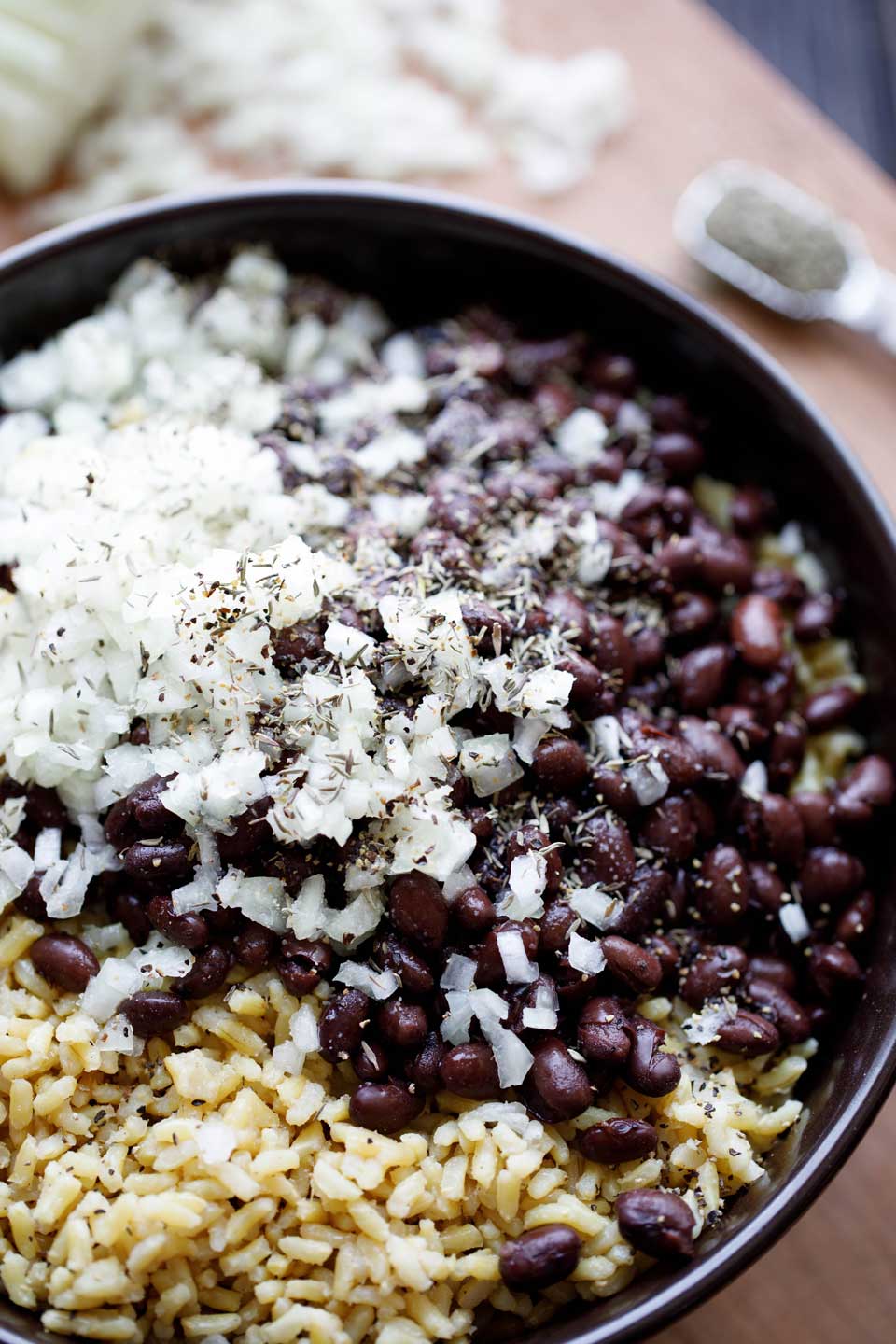 Recipe ingredients piled in a bowl, ready to mix together - black beans, rice, onions and spices