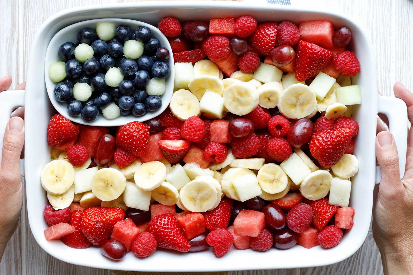 Flag fruit salad in a rectangle pan - rows of red and white fruit with a blue area dotted with white melon balls to make stars