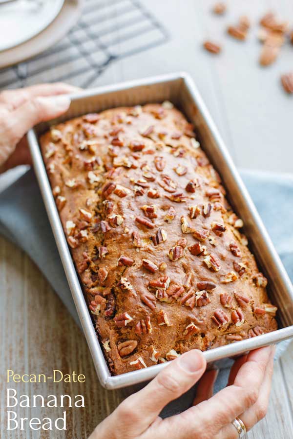 Loaf of Whole Wheat Banana Bread in baking pan with text overlay "Pecan-Date Banana Bread"