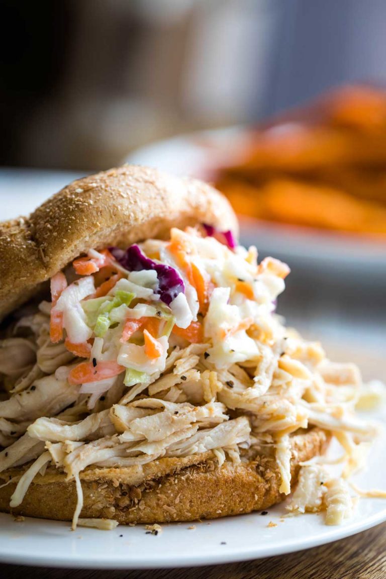 Closeup side view of one piled-high sandwich topped with coleslaw.