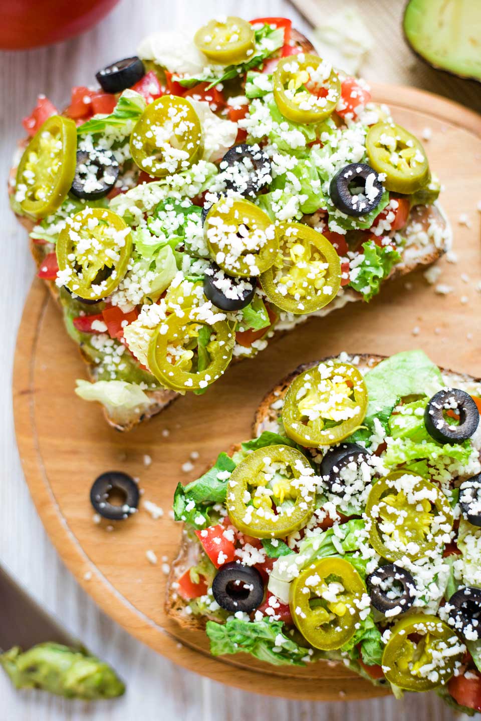 closeup of two pieces of this recipe's avocado toast, laying on a round wooden serving tray