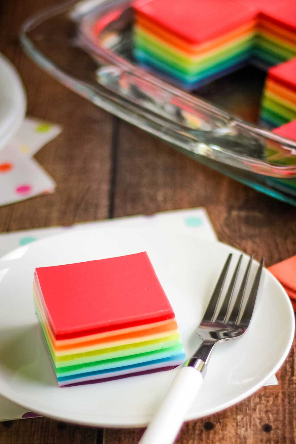 white plate with layered, rainbow jell-o and a fork