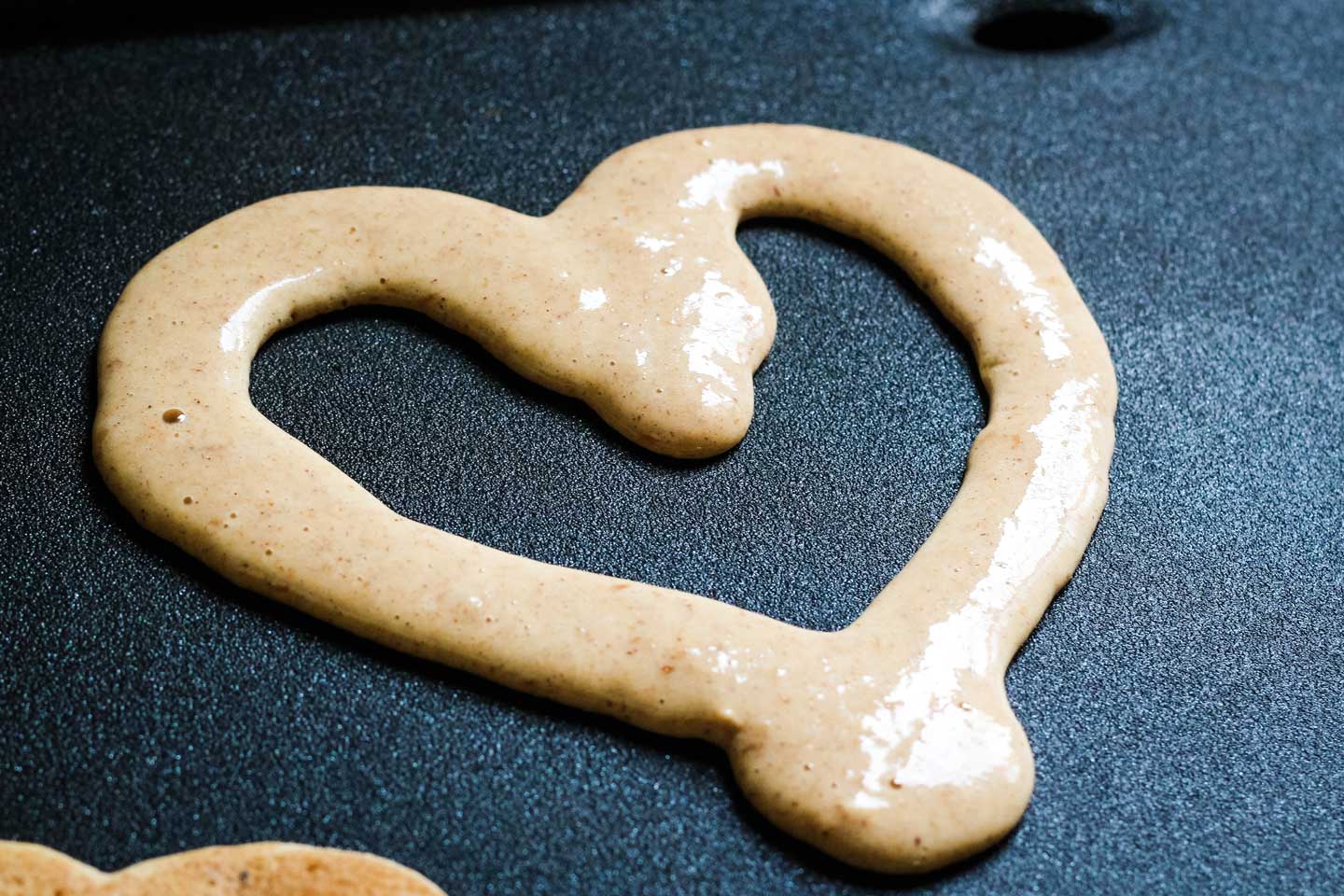skillet with a heart-shaped pancake cooking on it