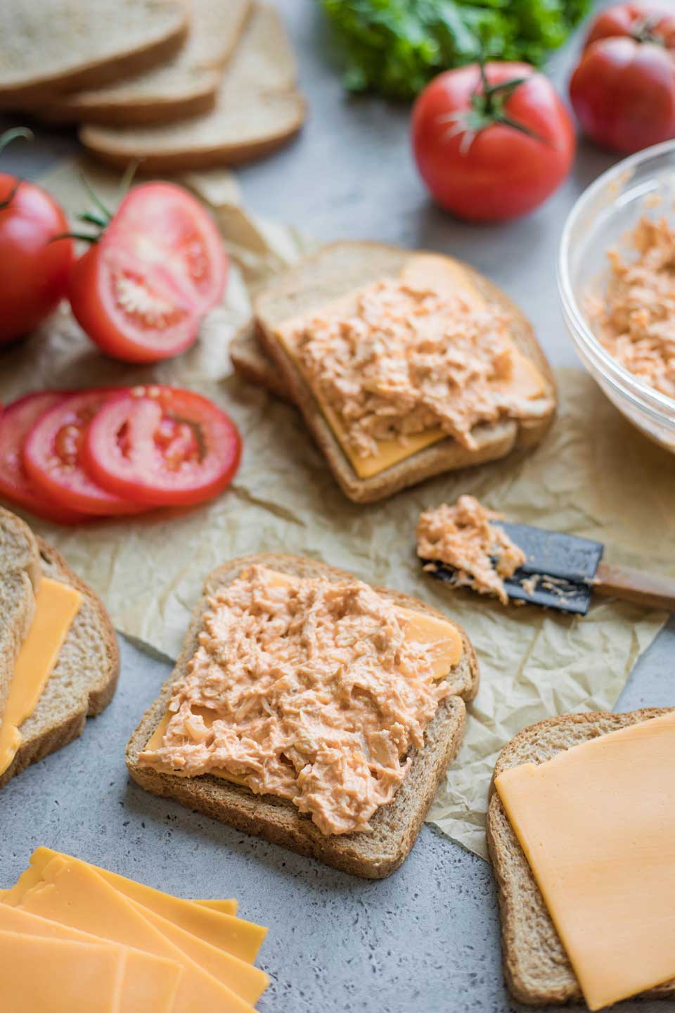 assembling the sandwiches: two slices of bread, each topped with a slice of cheese and spread with the Buffalo Chicken Dip filling