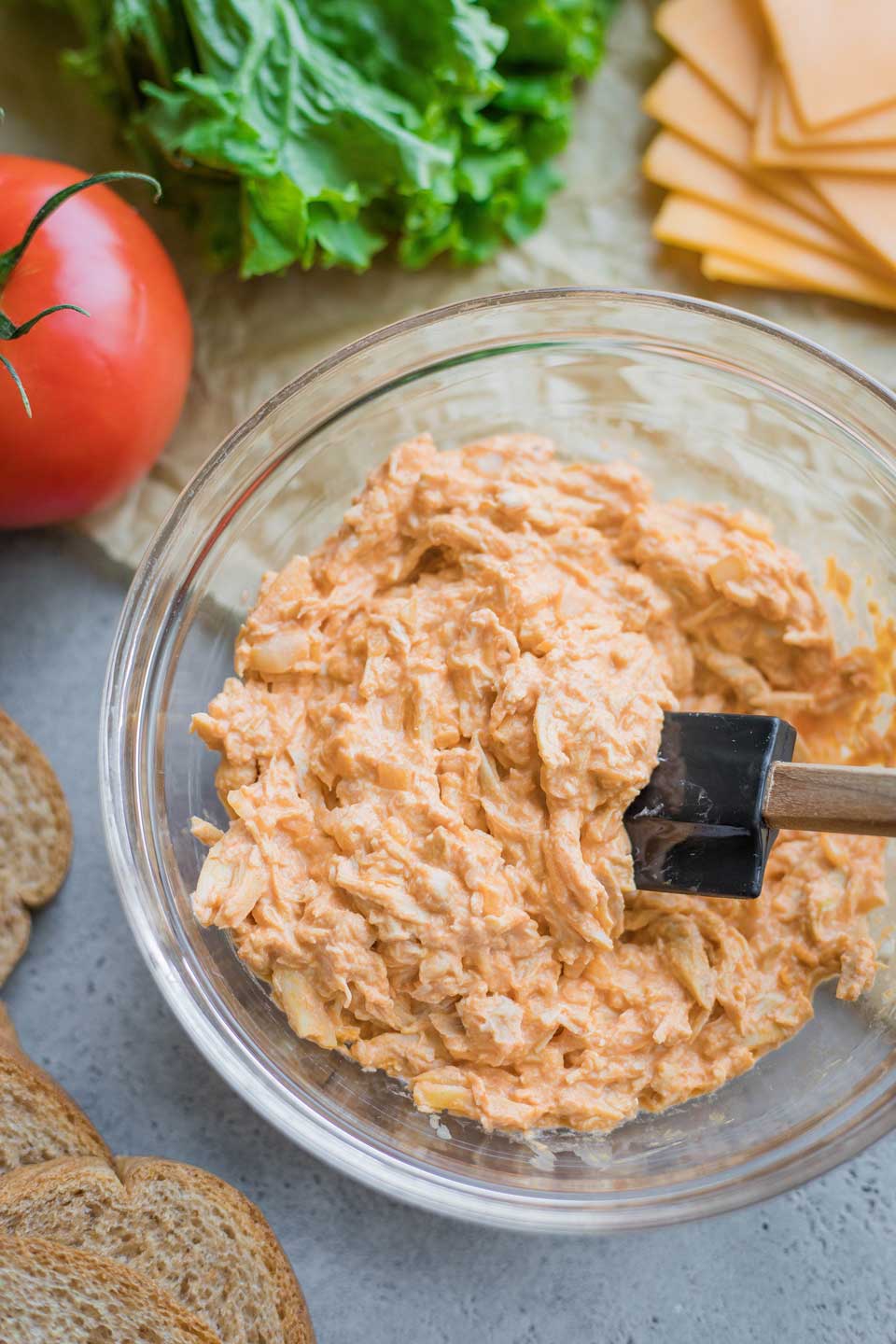 mixing bowl with Buffalo Chicken Dip filling, surrounded by other sandwich ingredients