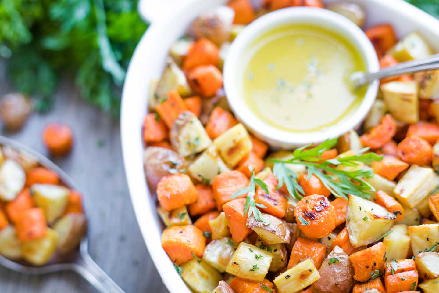 serving bowl piled with roasted vegetables, nestled alongside a small bowl of the drizzle