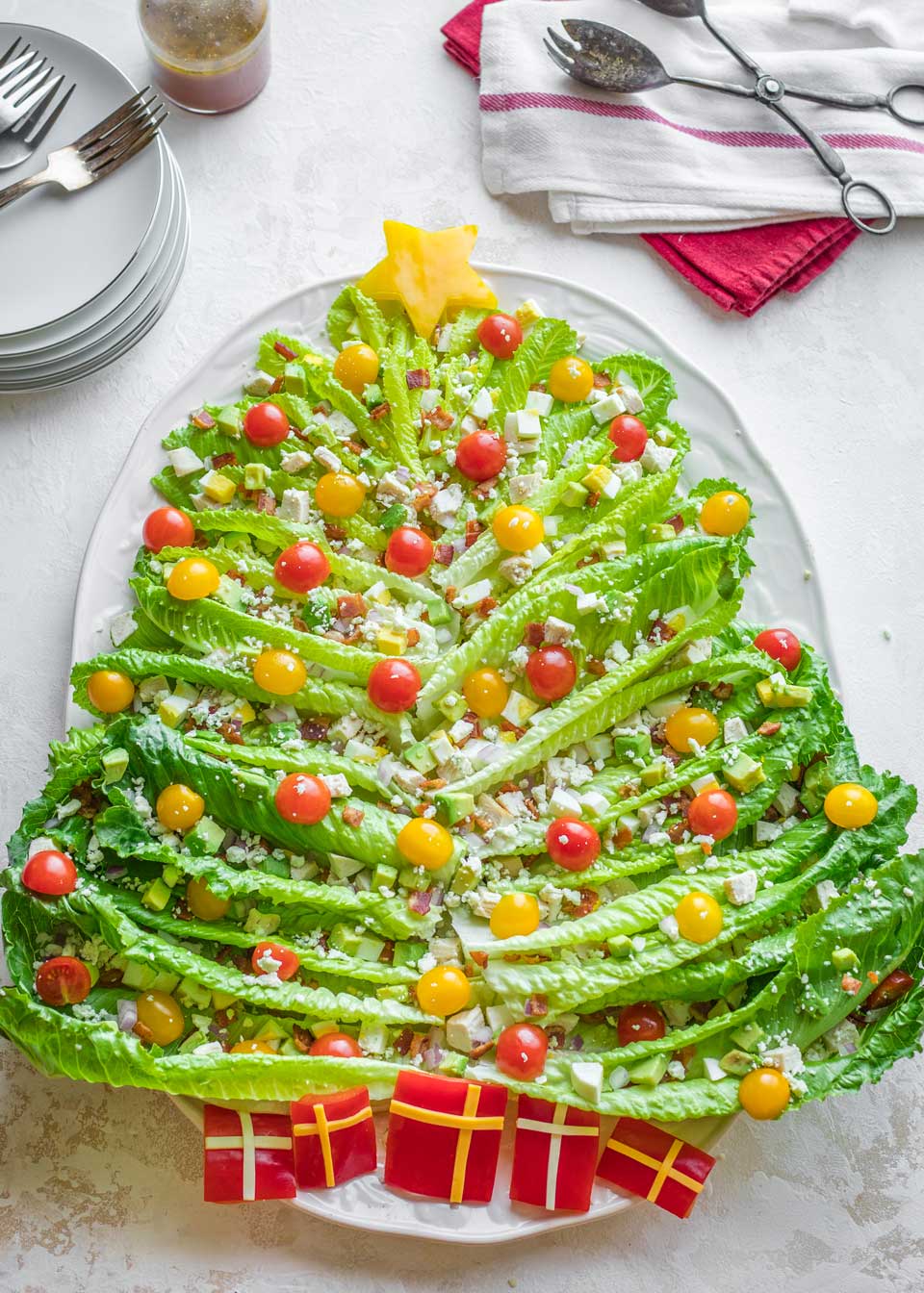 overhead of finished Christmas Tree-shaped holiday Salad, with salad tongs, forks and salad plates nearby
