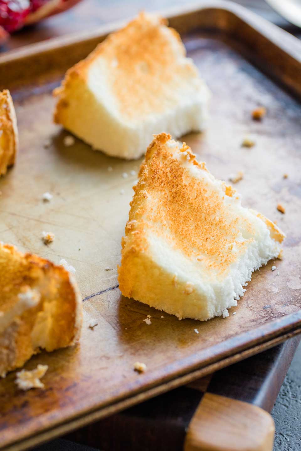 closeup of four slices of angel food cake on a baking sheet, toasted and golden brown after broiling