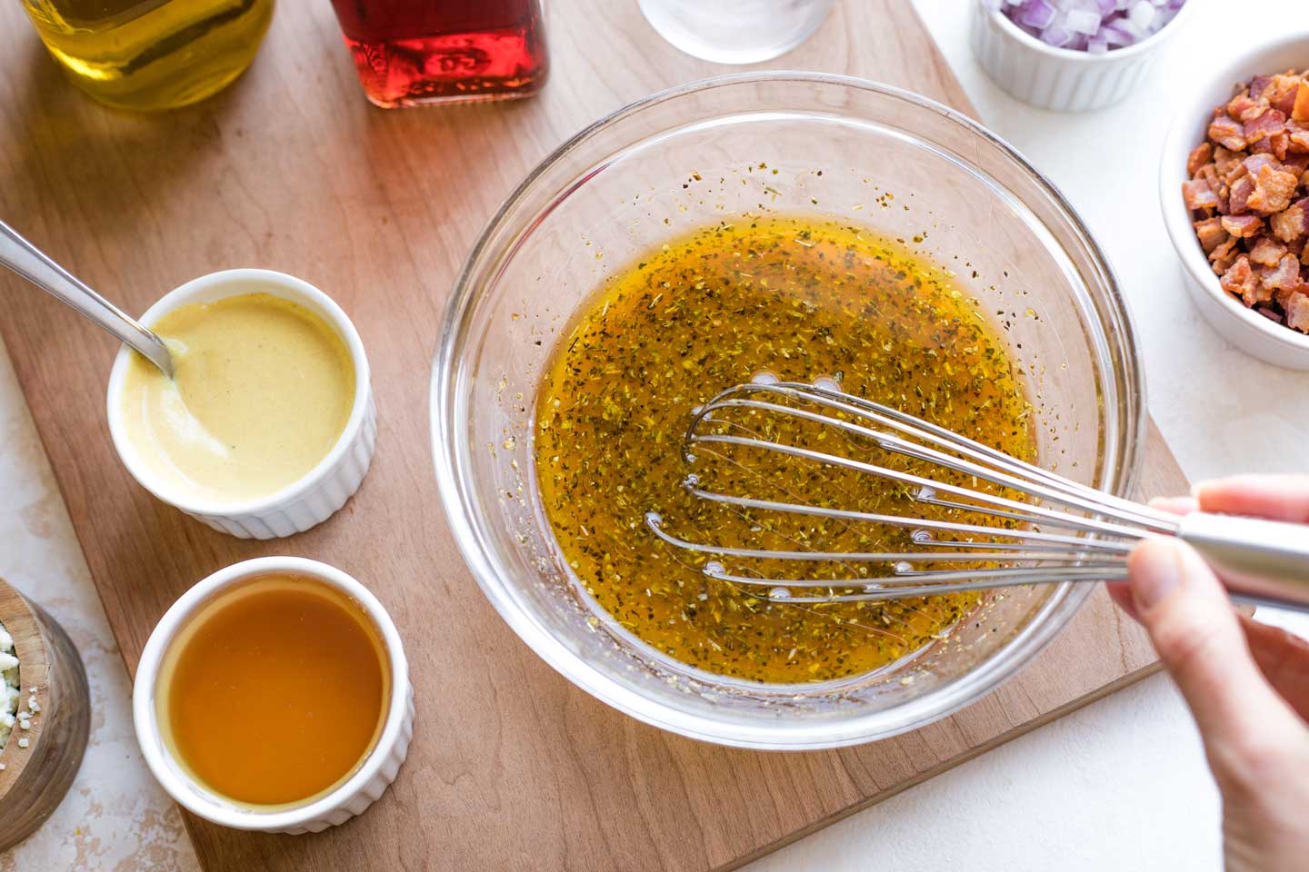bowl of vinaigrette ingredients on cutting board, being whisked together