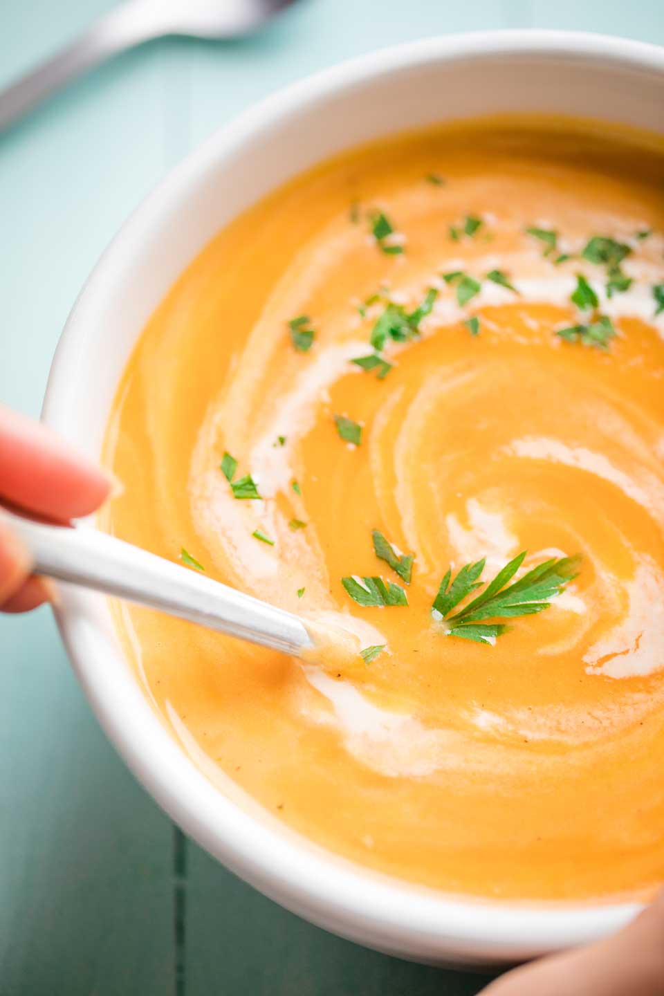 overhead photo of a hand grasping a spoon that's dipped into a bowl of our Instant Pot Sweet Potato Soup