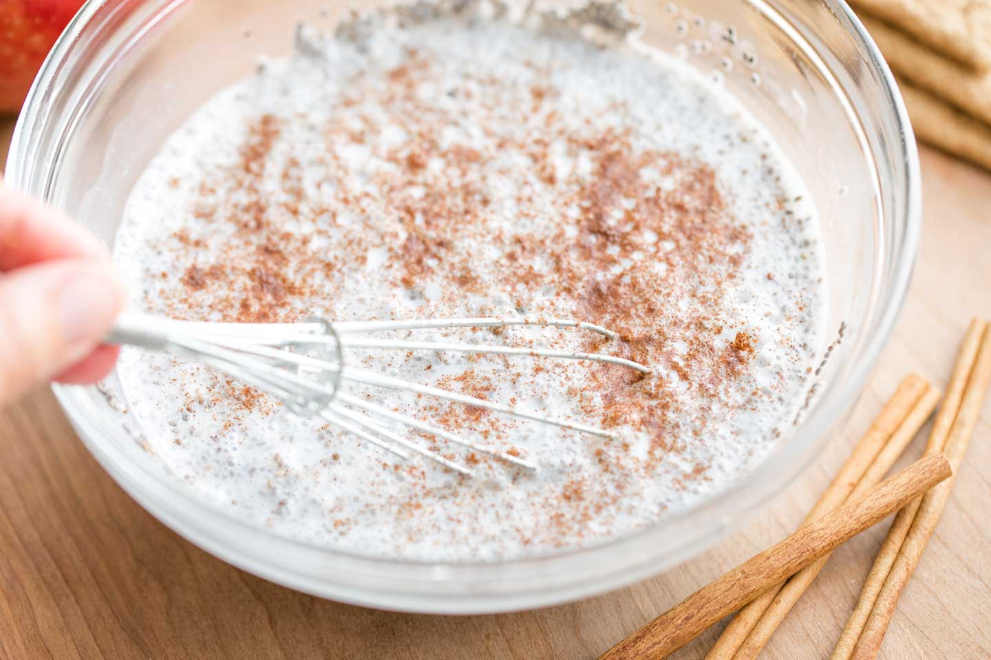 whisk combining cinnamon into pudding mixture that's in a glass mixing bowl