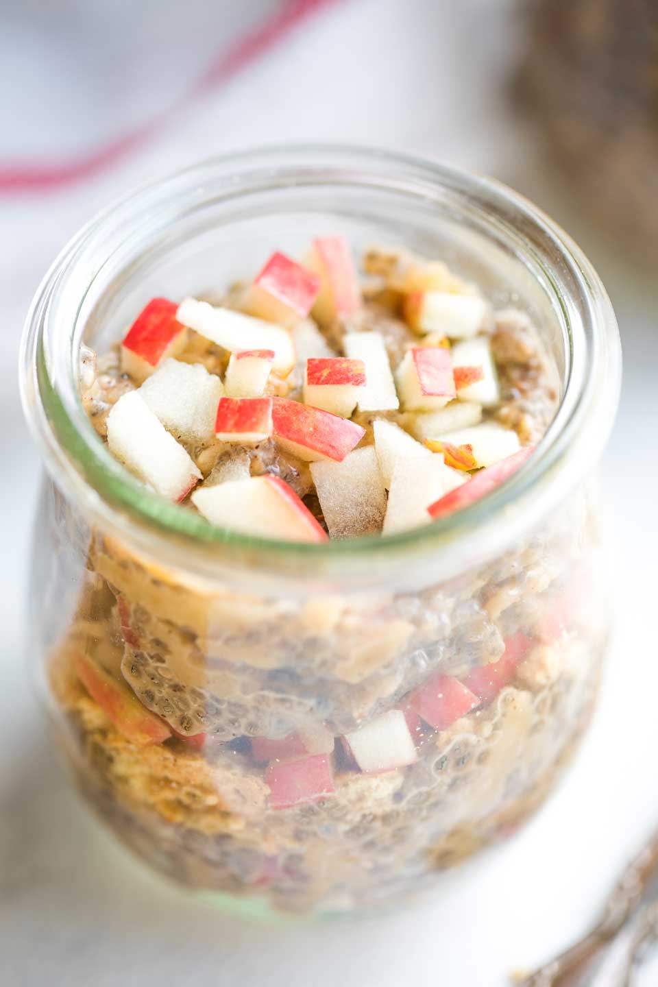 closeup of one jar of the pudding, served in layers with crumbled graham crackers and chopped bits of apple in between pudding layers