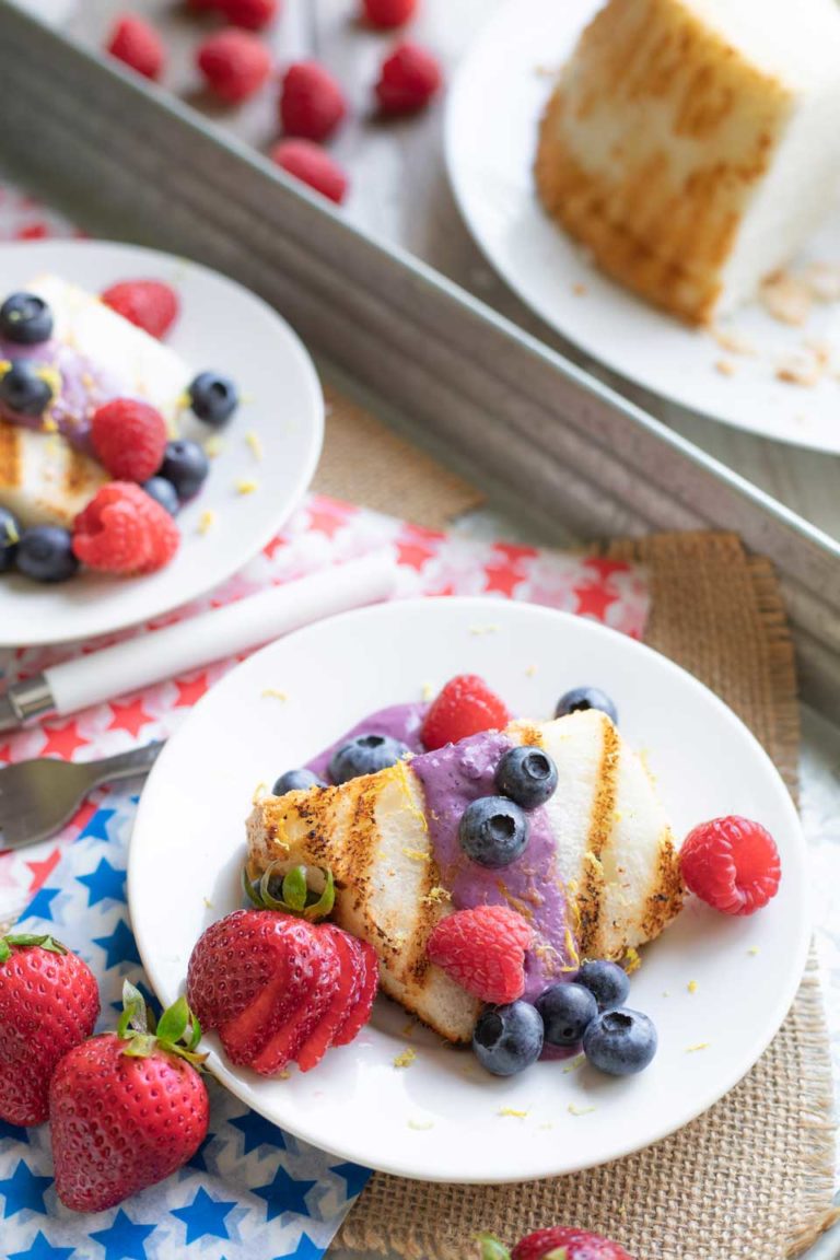 Plates of cake with strawberries and raspberries added, in addition to the blueberries for a red, white and blue look