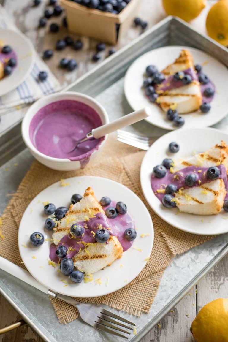 Several plates of dessert, all finished and laying on a serving tray with a little bowl of extra blueberry cream