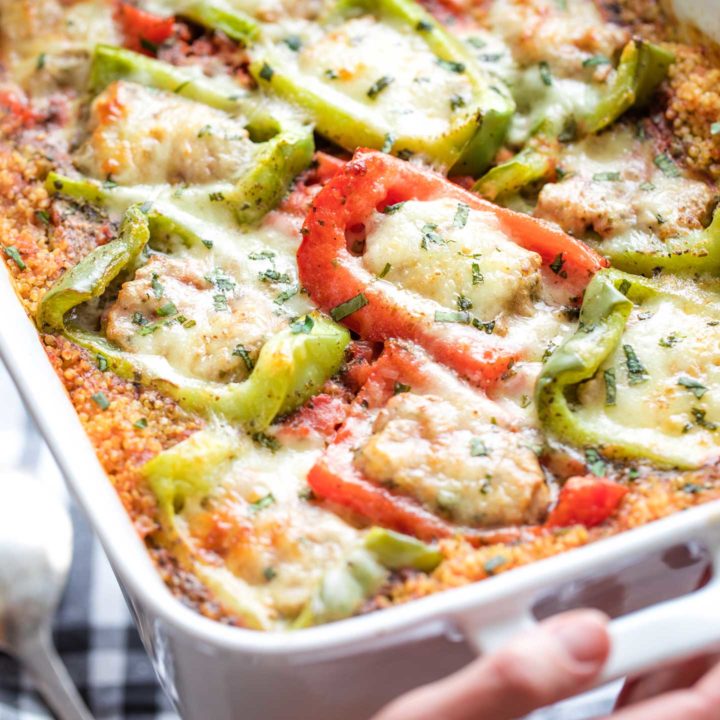 Closeup of a few of the cheese-topped peppers in this casserole, with hands holding the pan, fresh out of the oven.