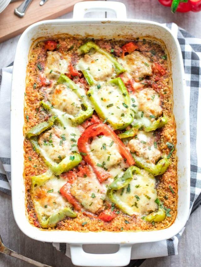 Overhead of the entire casserole pan of stuffed peppers, just out of the oven, laying on a dish towel with black checks, with a serving spoon alongside.