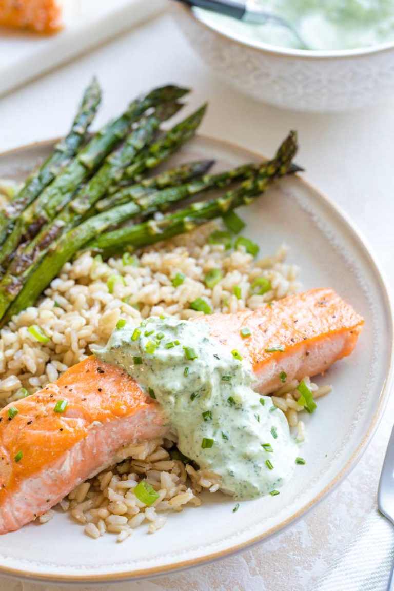 Completed meal of seared salmon with sauce, plated with rice and asparagus.