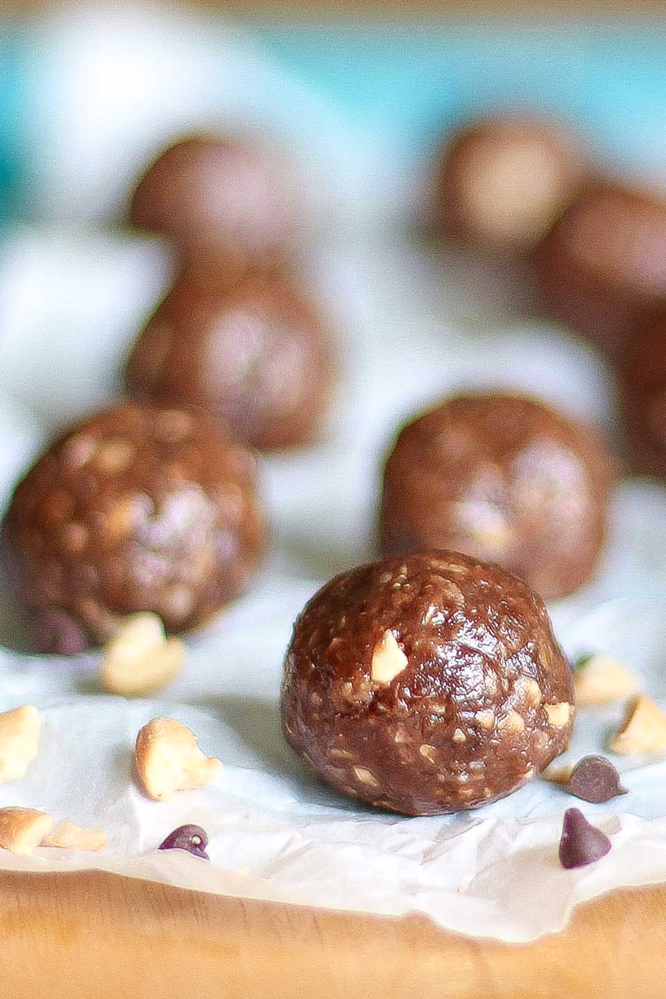 One chocolate peanut butter energy ball with several others out of focus nearby.
