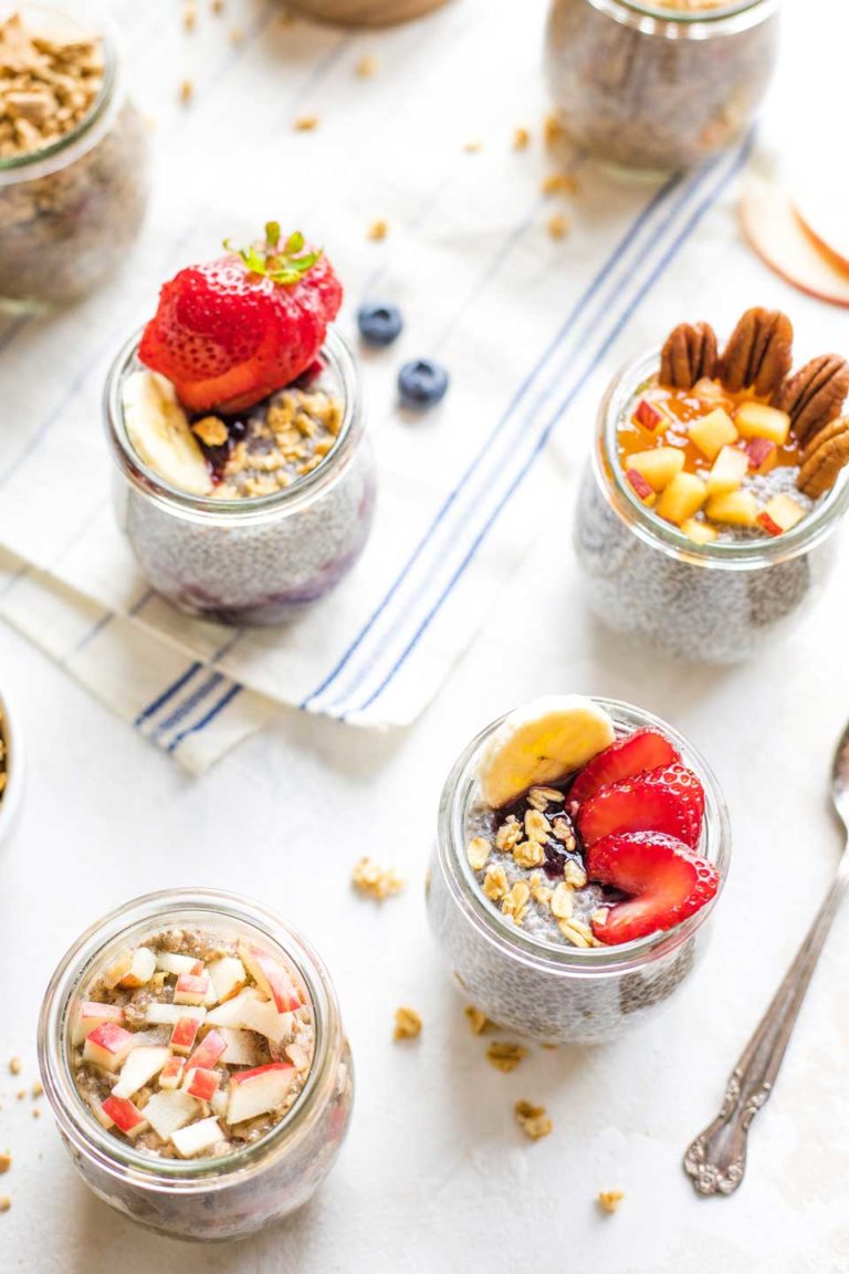 Overhead of several small jars with different chia pudding flavor combos and toppings.