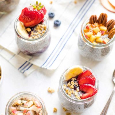 Pinnable image of several pre-portioned jars of Overnight Chia Pudding with different toppings.