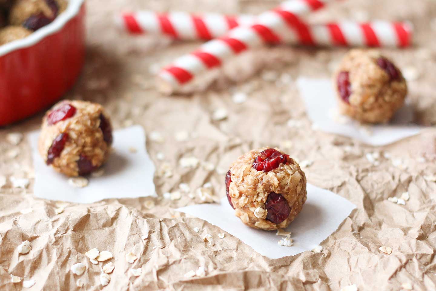 Three Energy Balls, each on a square of white paper, with festive straws in the background.