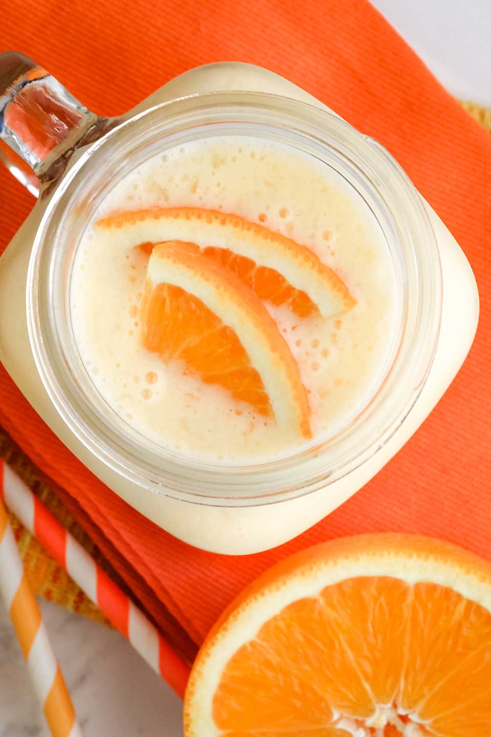 Top view of finished smoothie, with two sliced and quartered oranges floating on top.