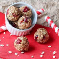 Two Energy Bites on a red napkin with several more balls piled in a white bowl behind.