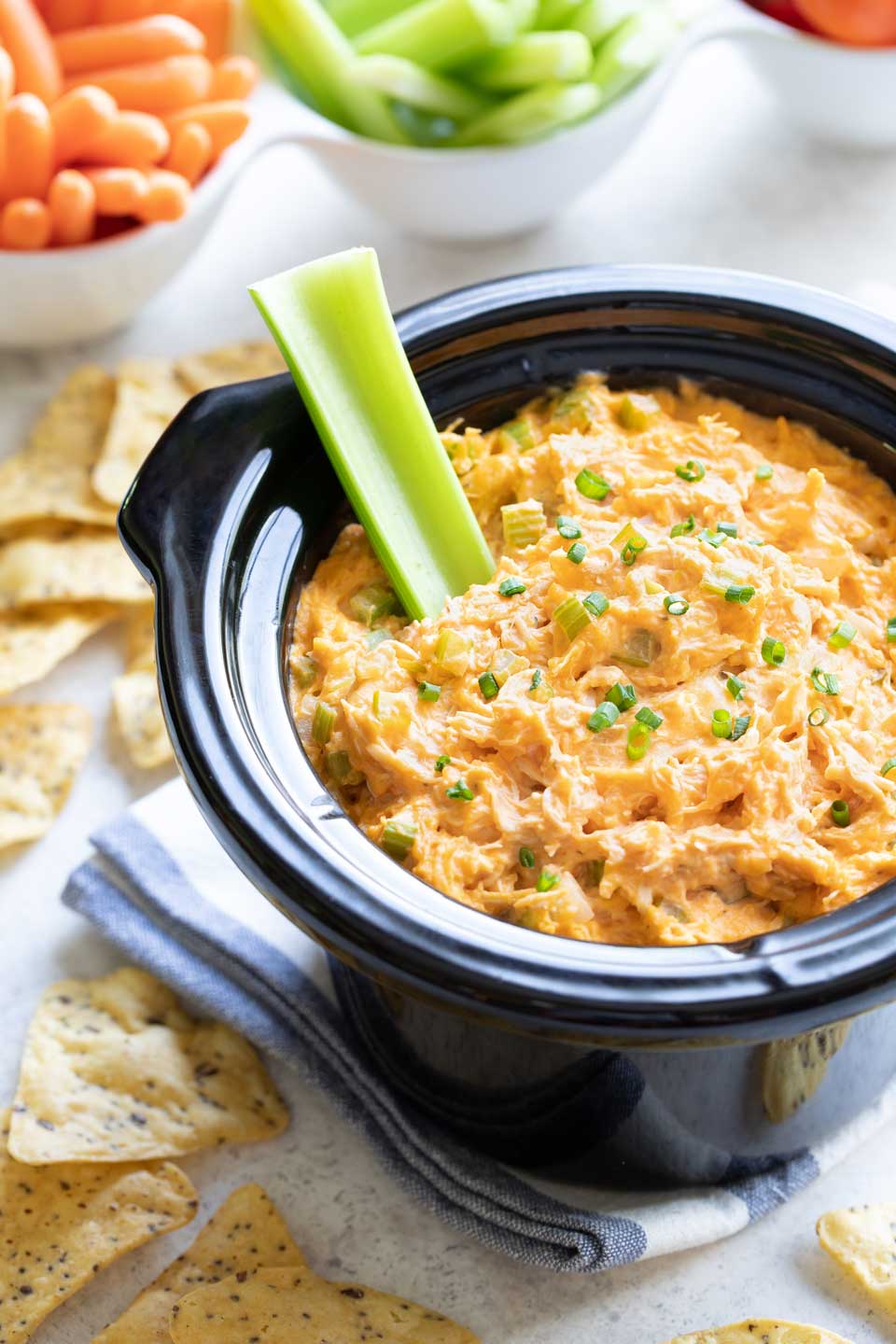 Appetizer dip in slow cooker with a celery stick stuck in.