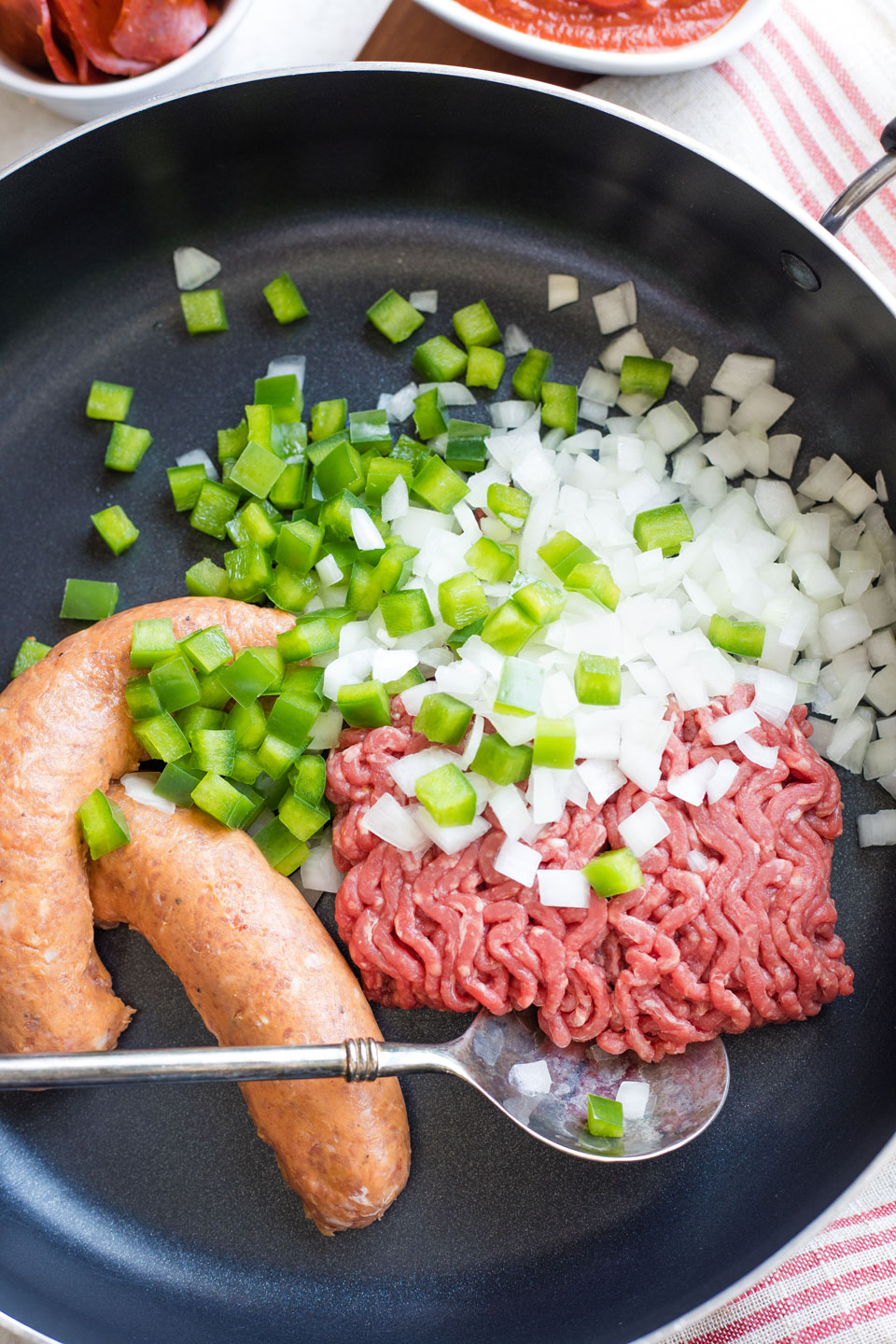 Nonstick skillet ready to cook Italian sausage, beef and diced veggies.