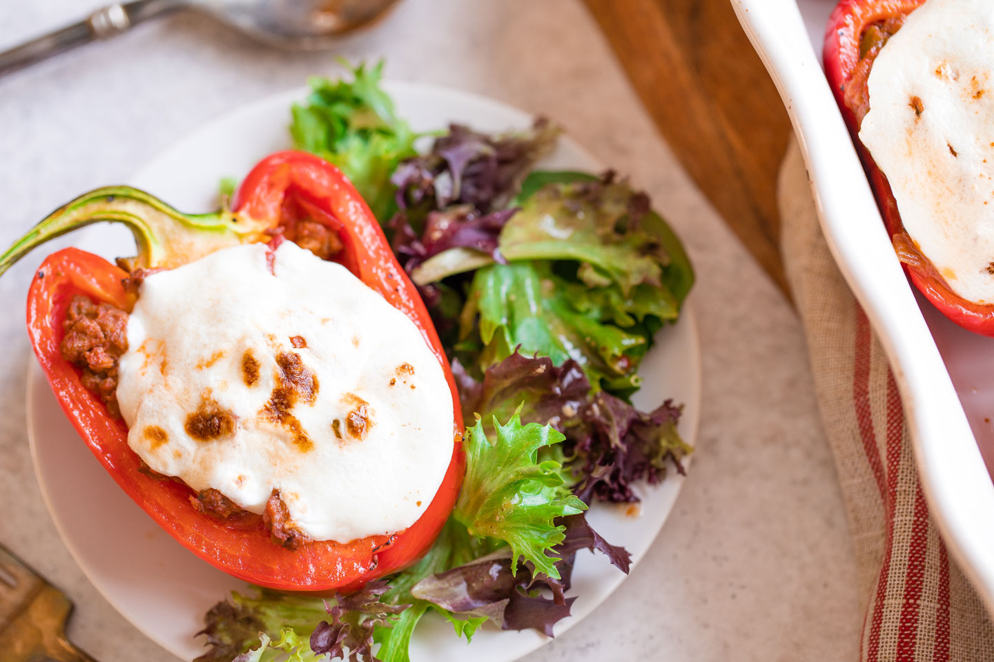 One stuffed pepper on a white plate with Italian salad.